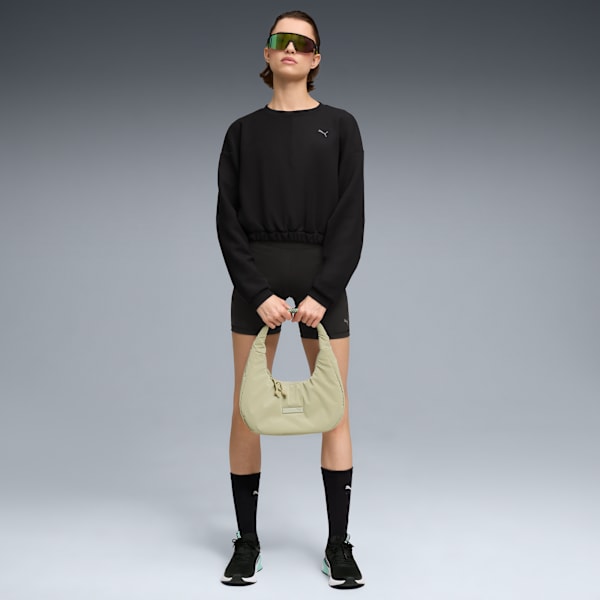 A model stands against grey, holding a light green bag, and wearing black sportswear.