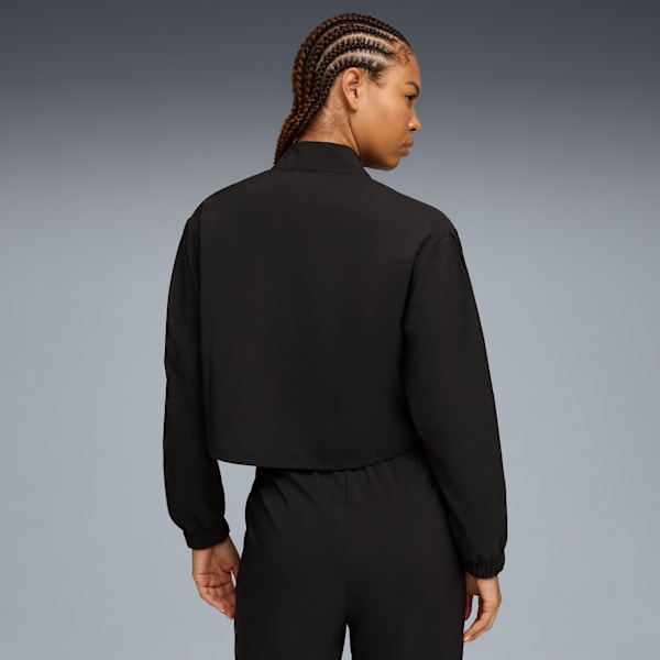 A model poses against a grey backdrop, wearing a black jacket and trousers.