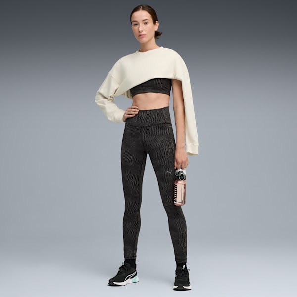 A model poses against a grey backdrop, wearing sportswear and holding a water bottle.