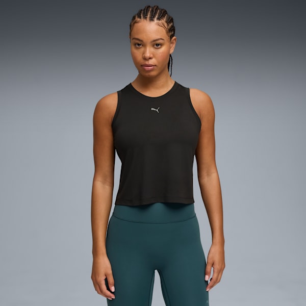 Against grey, a model poses in a black top and teal leggings, facing forward.