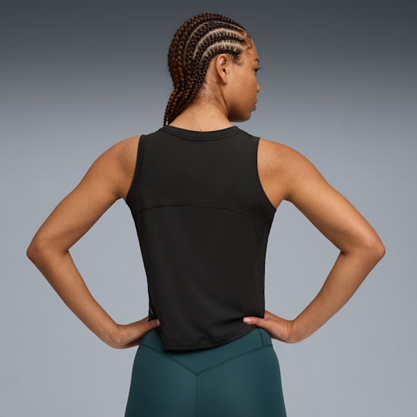 A model poses against a grey backdrop, wearing a black top and teal leggings.