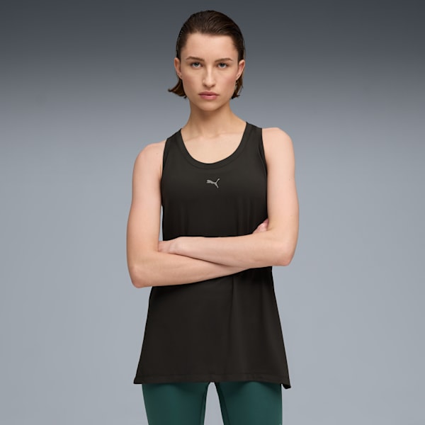 Against a grey backdrop, a model poses with arms crossed, wearing a black top and green leggings.