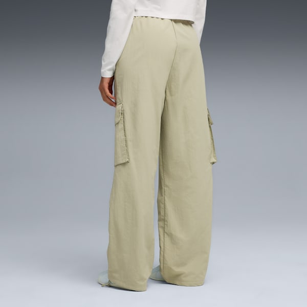 Model faces away on grey, wearing a white top and khaki wide-leg trousers.