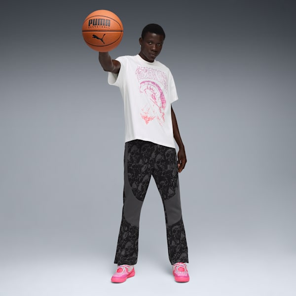 Model with basketball in front of grey background wearing t-shirt, trousers and trainers.