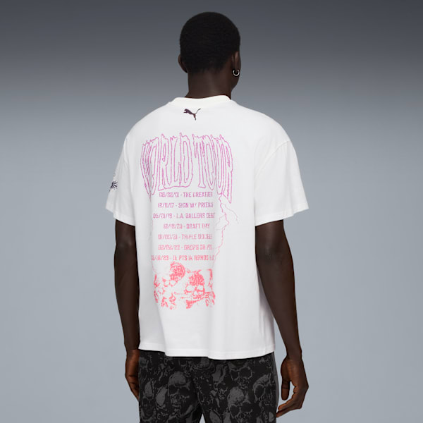 A model faces away against grey, wearing a white tee with pink tour graphic and skull print shorts.