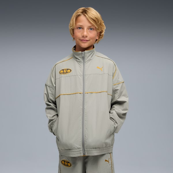 A model poses against a grey backdrop, wearing a grey Puma tracksuit with gold accents.