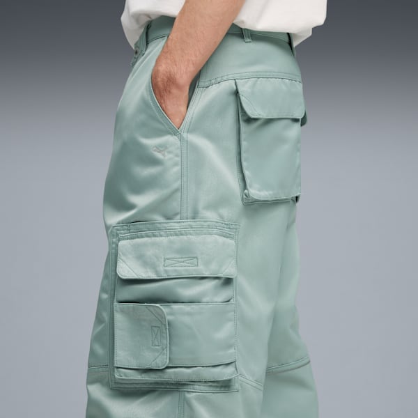 A model poses against grey, wearing light-green cargo trousers with hand in pocket.
