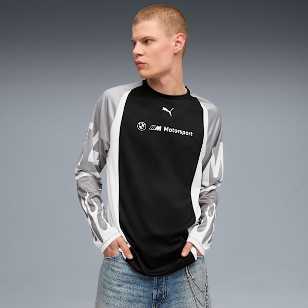 Against grey, a model poses in a long-sleeved shirt with BMW Motorsport branding.