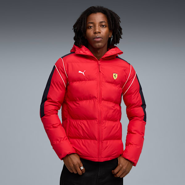 A model poses against a grey backdrop, wearing a red puffer jacket with logos.