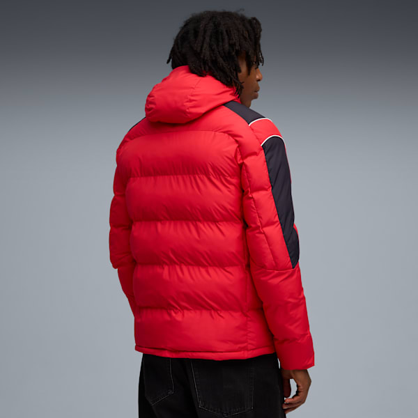 Against grey, a model faces away, wearing a red hooded puffer jacket and dark jeans.