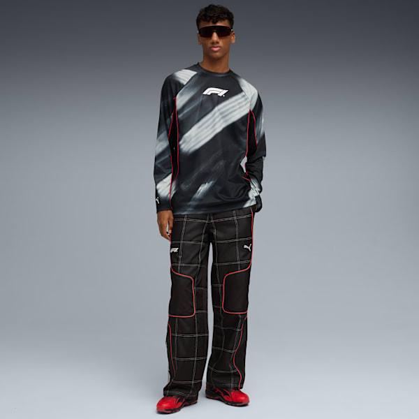A model poses against a grey backdrop, wearing a patterned top, trousers and red shoes.
