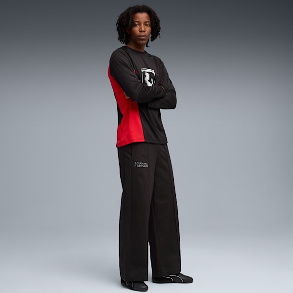 A model stands against grey wearing a black and red long-sleeve top and black trousers.