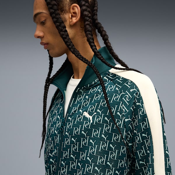 A model against a grey backdrop wears a patterned teal jacket with a white stripe and a white t-shirt.