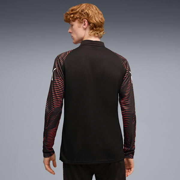 A model stands against a grey backdrop, wearing a black top with patterned sleeves.