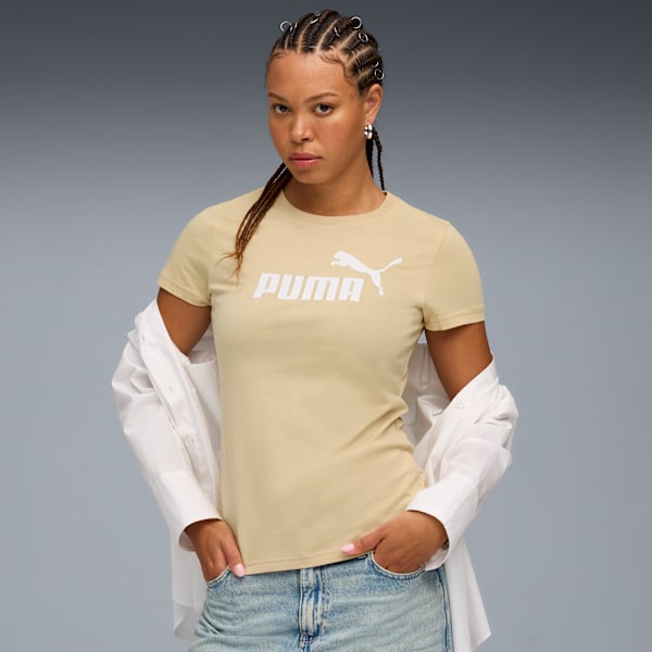 A model poses against a grey backdrop, wearing a beige Puma t-shirt and jeans.