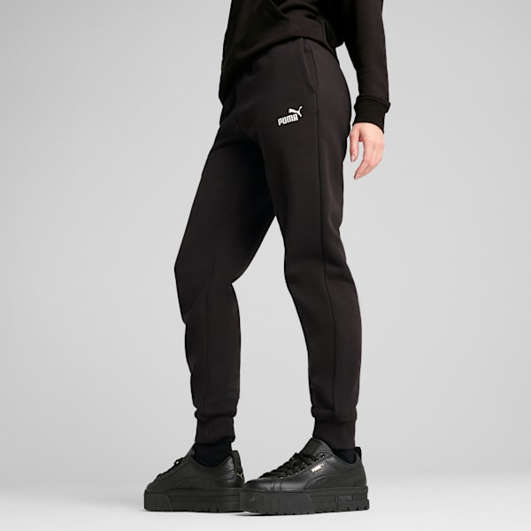 A model poses against grey wearing black joggers and matching platform trainers.