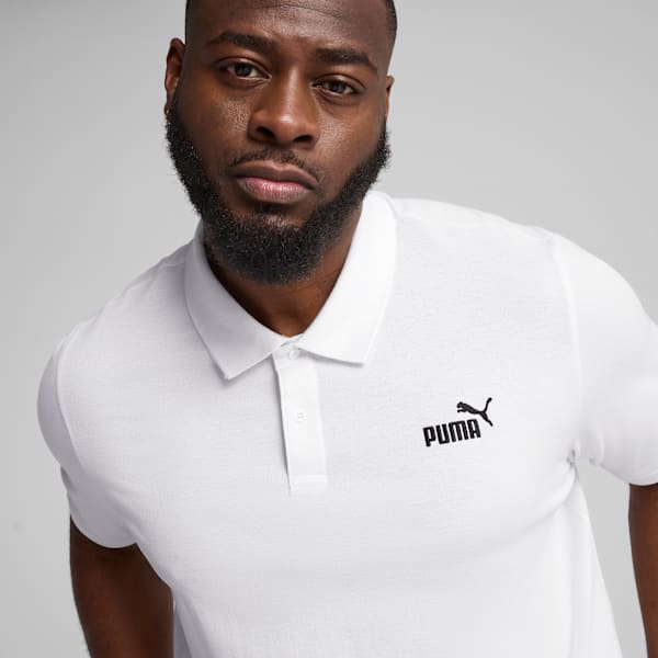 A model wears a white polo shirt with a black logo against a grey backdrop.