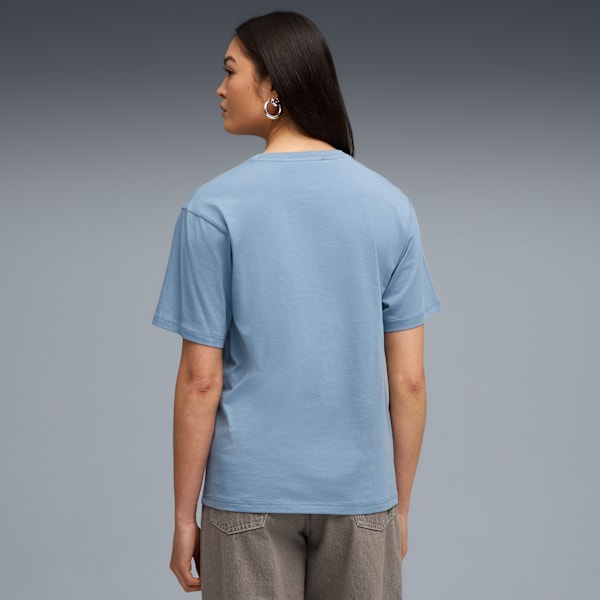 A model faces left against grey, wearing a blue t-shirt and brown shorts.