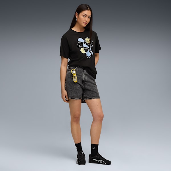 A model poses against a grey backdrop, wearing a graphic t-shirt, shorts and trainers.