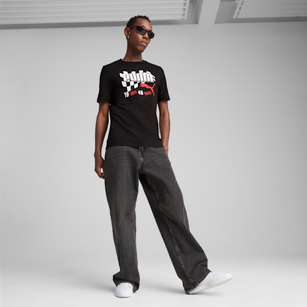 A model in front of a grey backdrop wearing a logo t-shirt, jeans, and trainers.