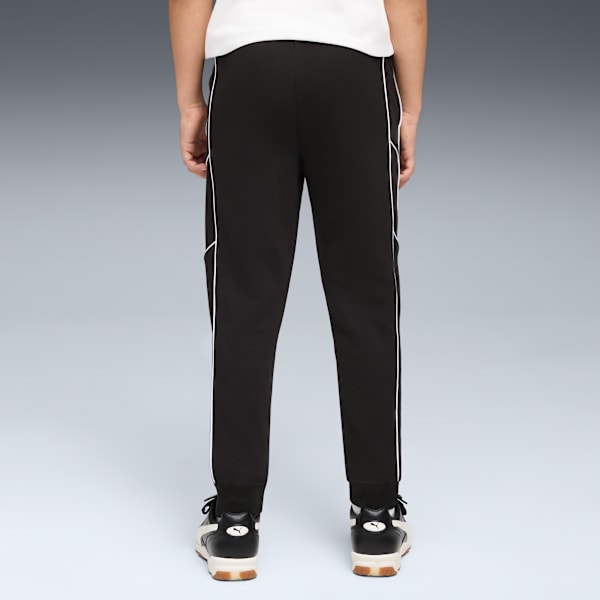 Seen from behind, a model wears black track pants with white stripes and trainers.