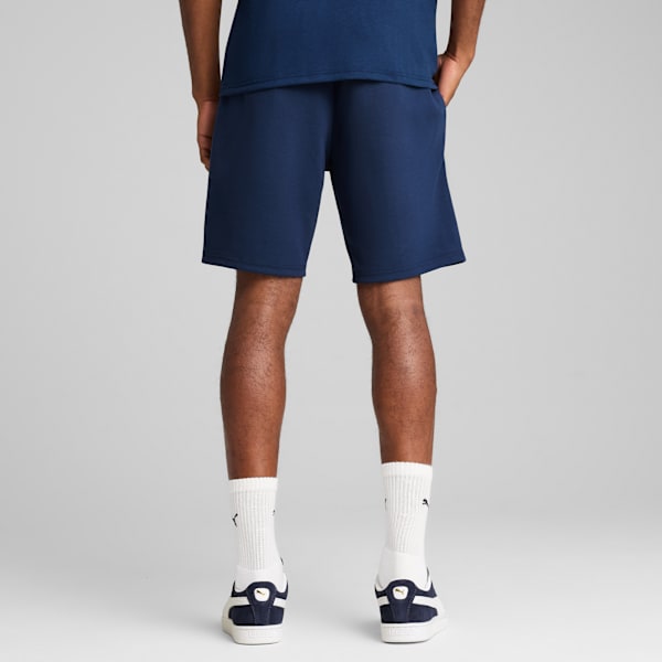 Seen from behind, a model poses against grey wearing a blue t-shirt, shorts, socks and trainers.