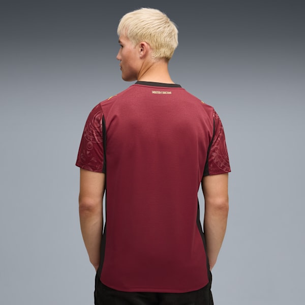 A model stands against a grey backdrop, showcasing a maroon t-shirt with short sleeves.