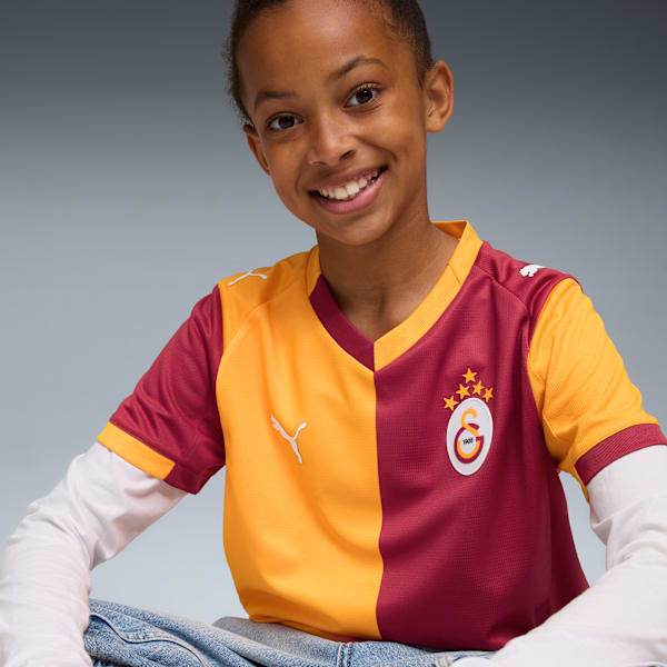 A smiling child models a two-tone sports shirt against a grey backdrop.