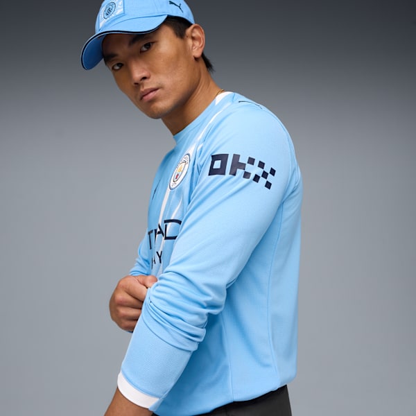 A model poses against a grey backdrop, wearing a light blue long-sleeved shirt and matching cap.