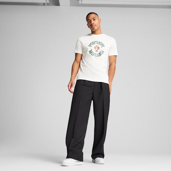 A model stands against a grey backdrop, wearing a Portugal t-shirt and black trousers.