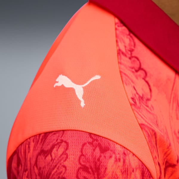 Close-up of a red and coral shirt with a white Puma logo on the sleeve.