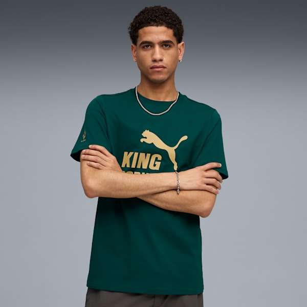 A model with crossed arms wears a green 'KING' t-shirt against a grey backdrop.