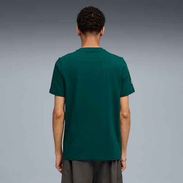 Seen from behind, a model wears a dark green t-shirt and grey shorts against a grey backdrop.