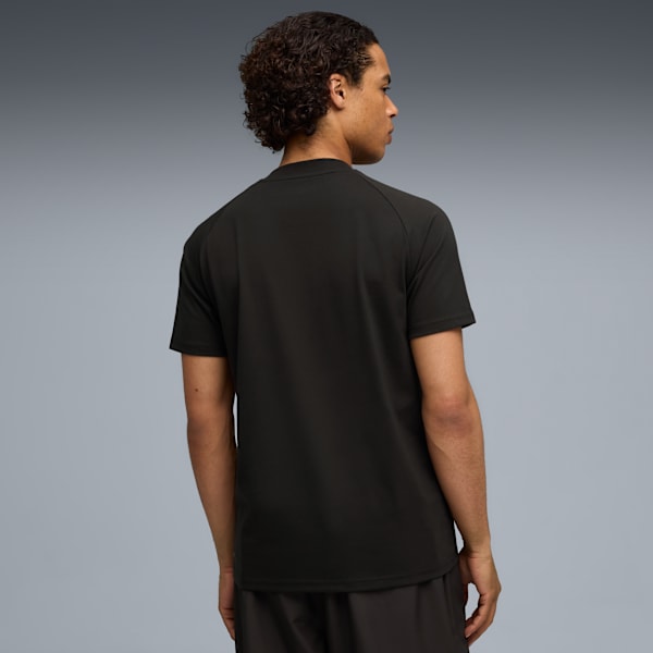 A model faces away on a grey background, wearing a dark t-shirt and shorts.