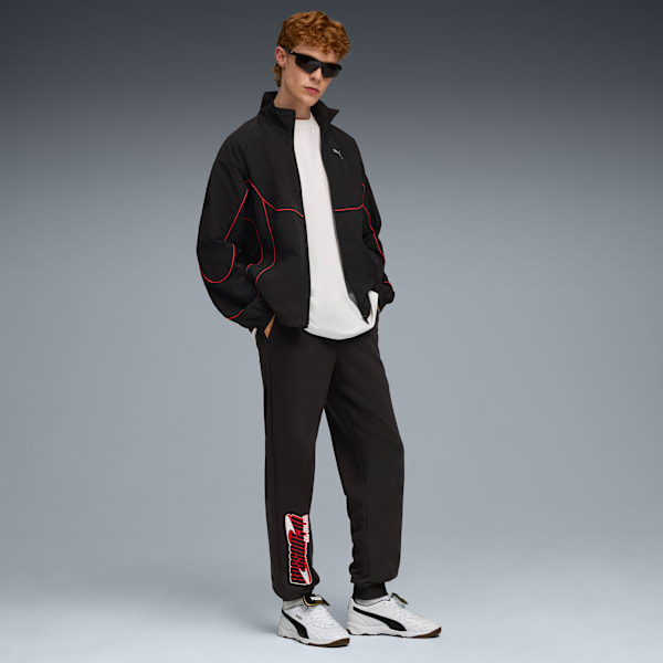 A model poses on a grey backdrop wearing a jacket, t-shirt, trousers and trainers.