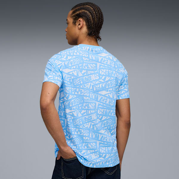 A model faces away in front of a grey background, wearing a blue and white patterned t-shirt.