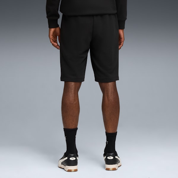 A model faces away in black shorts, socks, and shoes against a grey backdrop.