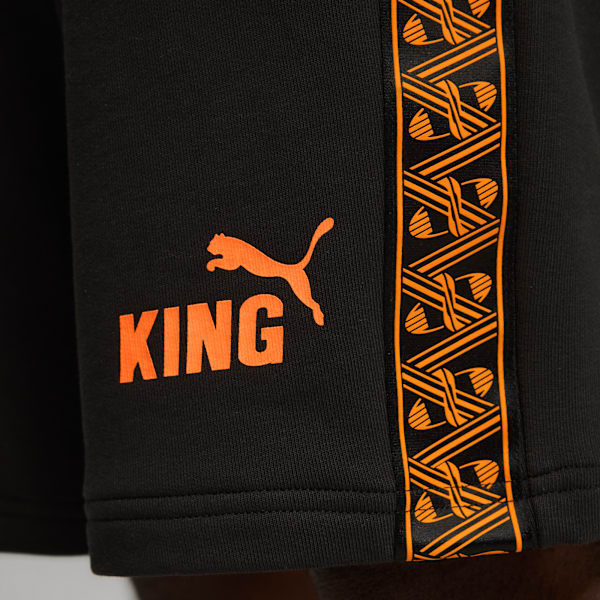 Close-up of black shorts with orange 'KING' text, Puma logo, and patterned stripe.