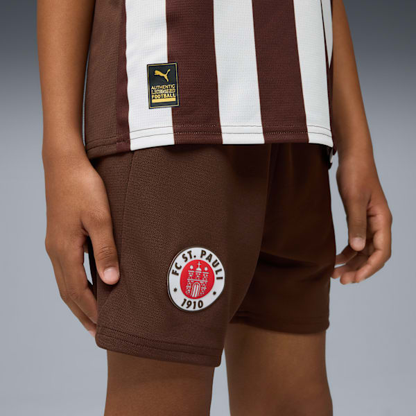 Torso of a model wearing a striped shirt and brown shorts with the FC St. Pauli logo.