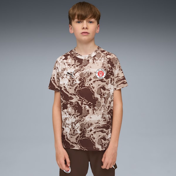 Against a grey backdrop, a model poses in a patterned t-shirt and shorts.