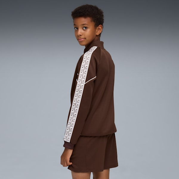 Against grey, a child models a brown tracksuit with patterned white stripes.