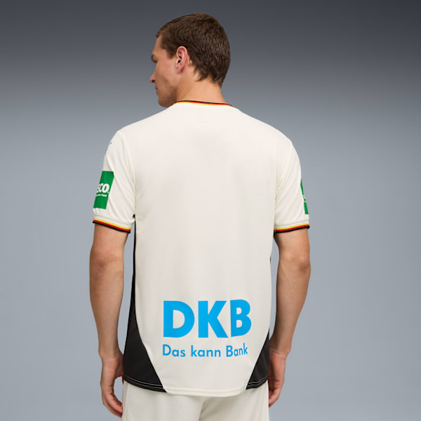 A model faces away against grey backdrop, wearing a white jersey with the DKB logo.