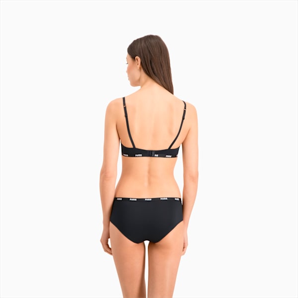 Against a white backdrop, a model faces away, wearing a black bra and briefs set.