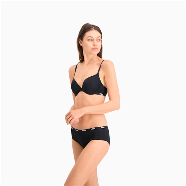 Against a white backdrop, a model poses in a black bra and briefs set.