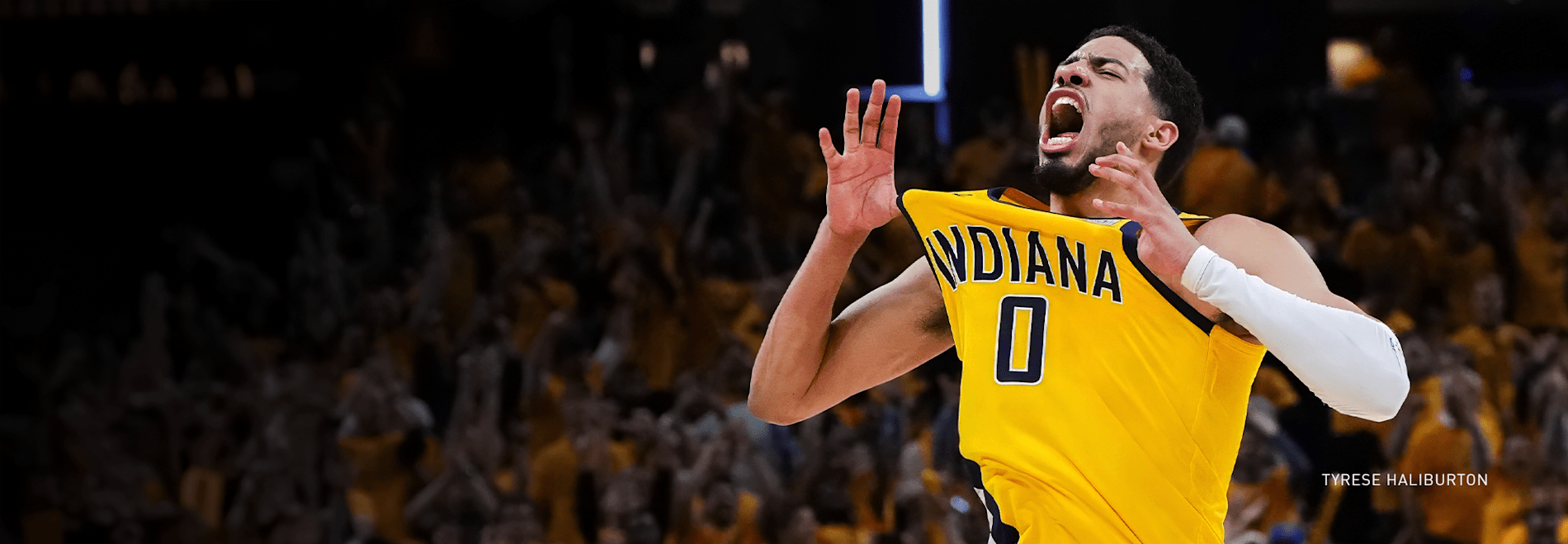 Tyrese Haliburton in an Indiana jersey, cheers with raised arms in front of a crowd.