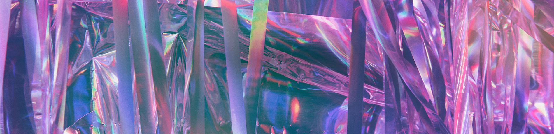 Abstract shot of a shiny, iridescent material with pink, blue and green hues.