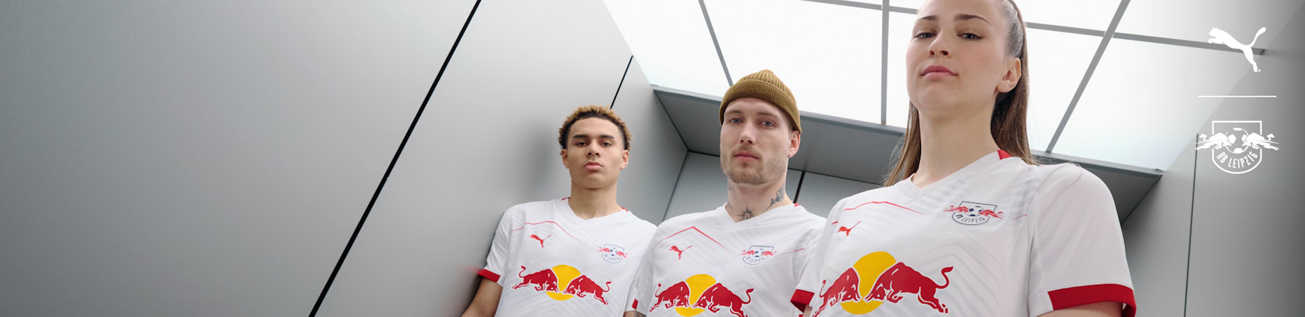 Three models pose in RB Leipzig home kit shirts against a modern, bright backdrop.