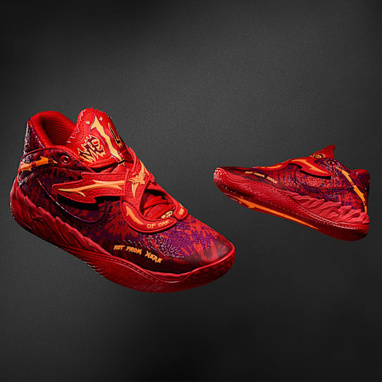 Against a dark backdrop, two red and orange MB.05 Crowd Surf basketball trainers are displayed.