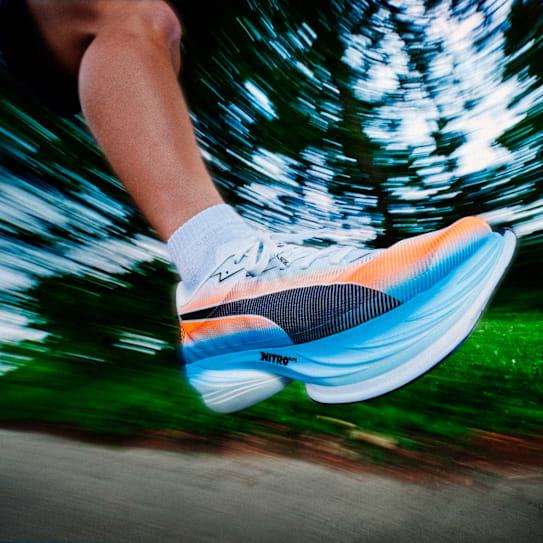 De voet van een hardloper met een kleurrijke Puma hardloopschoen in beweging, wazige achtergrond.