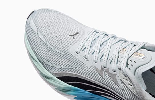 Close-up shows a light blue running shoe with laces against a plain background.